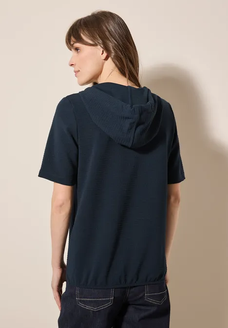 Frau mit dunkelblauem Kurzarm-Hoodie, von hinten fotografiert.